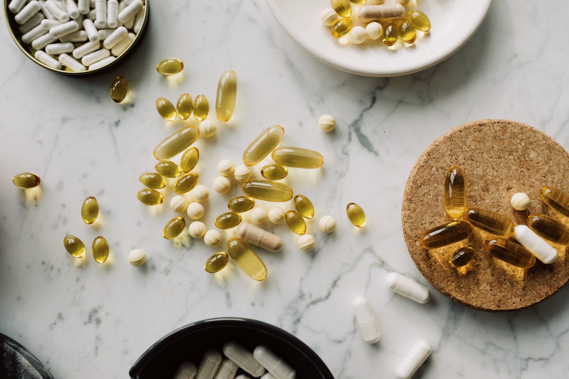 top view of various pills and vitamins placed in diverse utensil on marble board